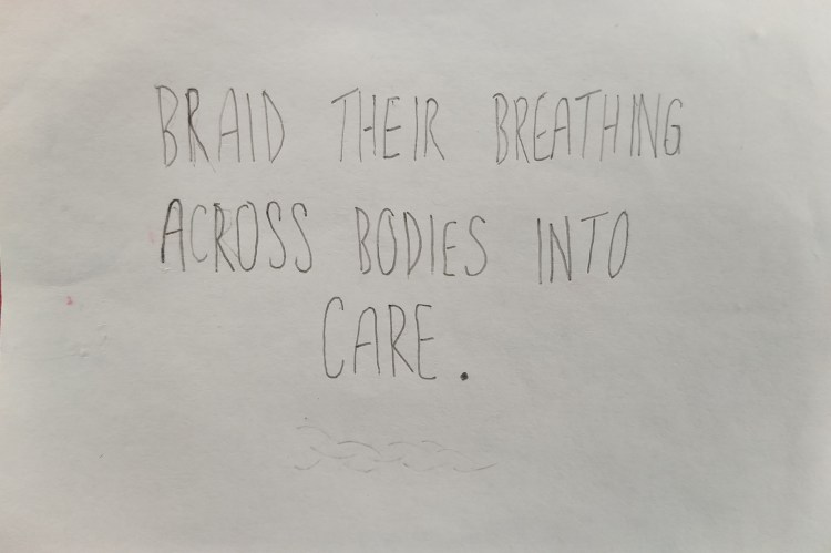 An index card on which the words "braid their breathing across bodies into care" are written in block capitals in pencil, below a faint trace of a braid has been sketched.