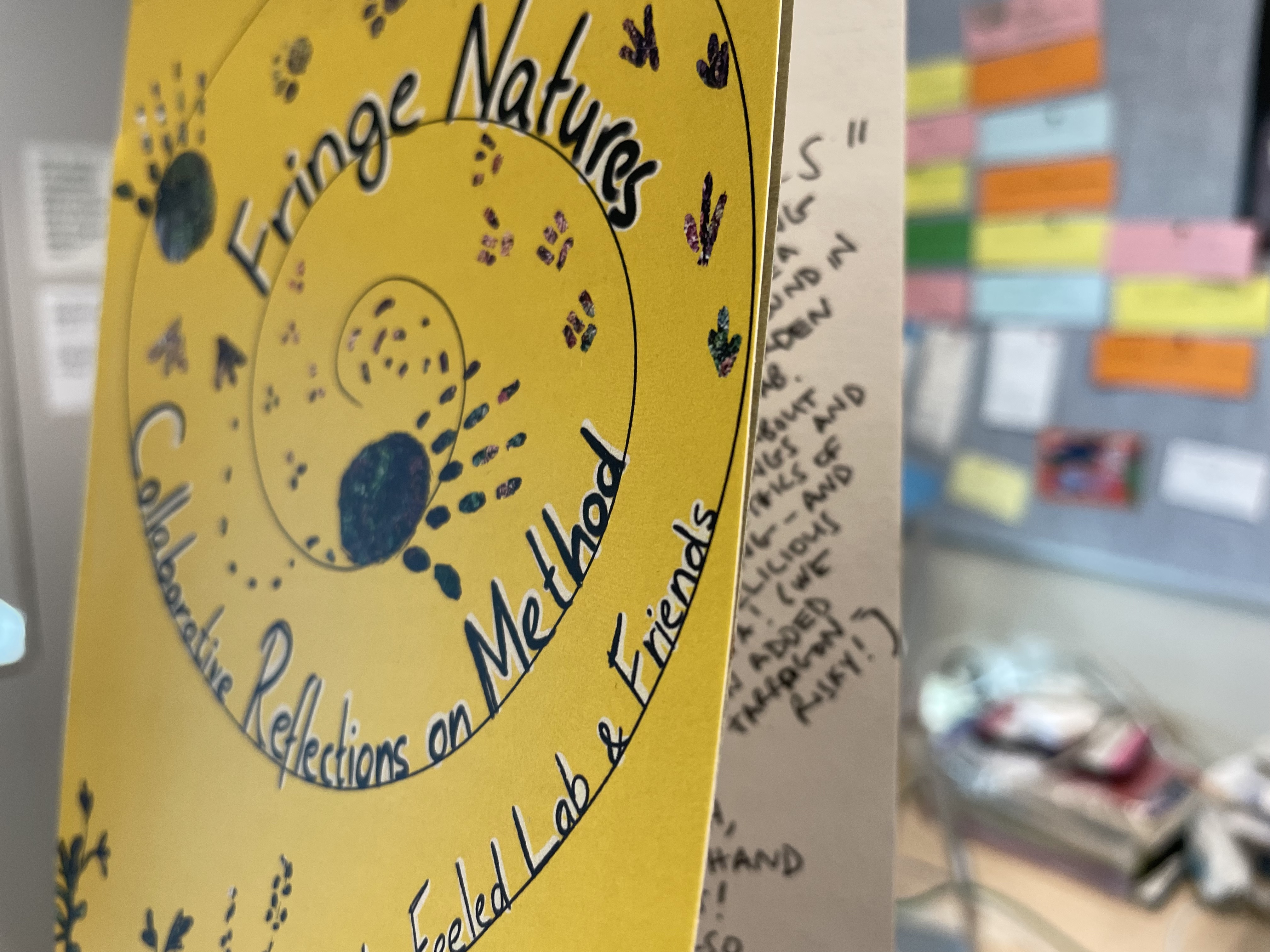 The cover of the yellow "Fringe Natures" zine is slightly open, revealing illegible text within.