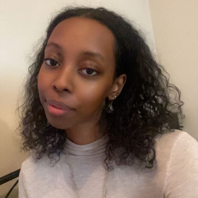 A softly smiling woman with dark curly hair