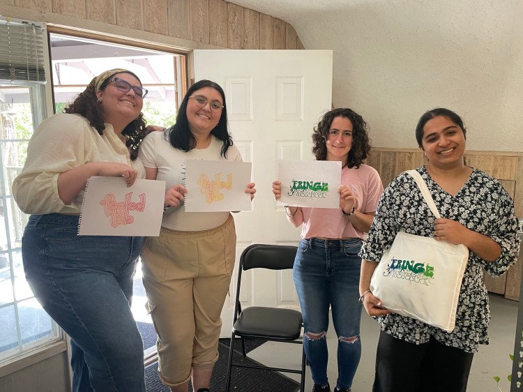 4 people stand by the door, proudly holding feeled lab and fringe natures prints