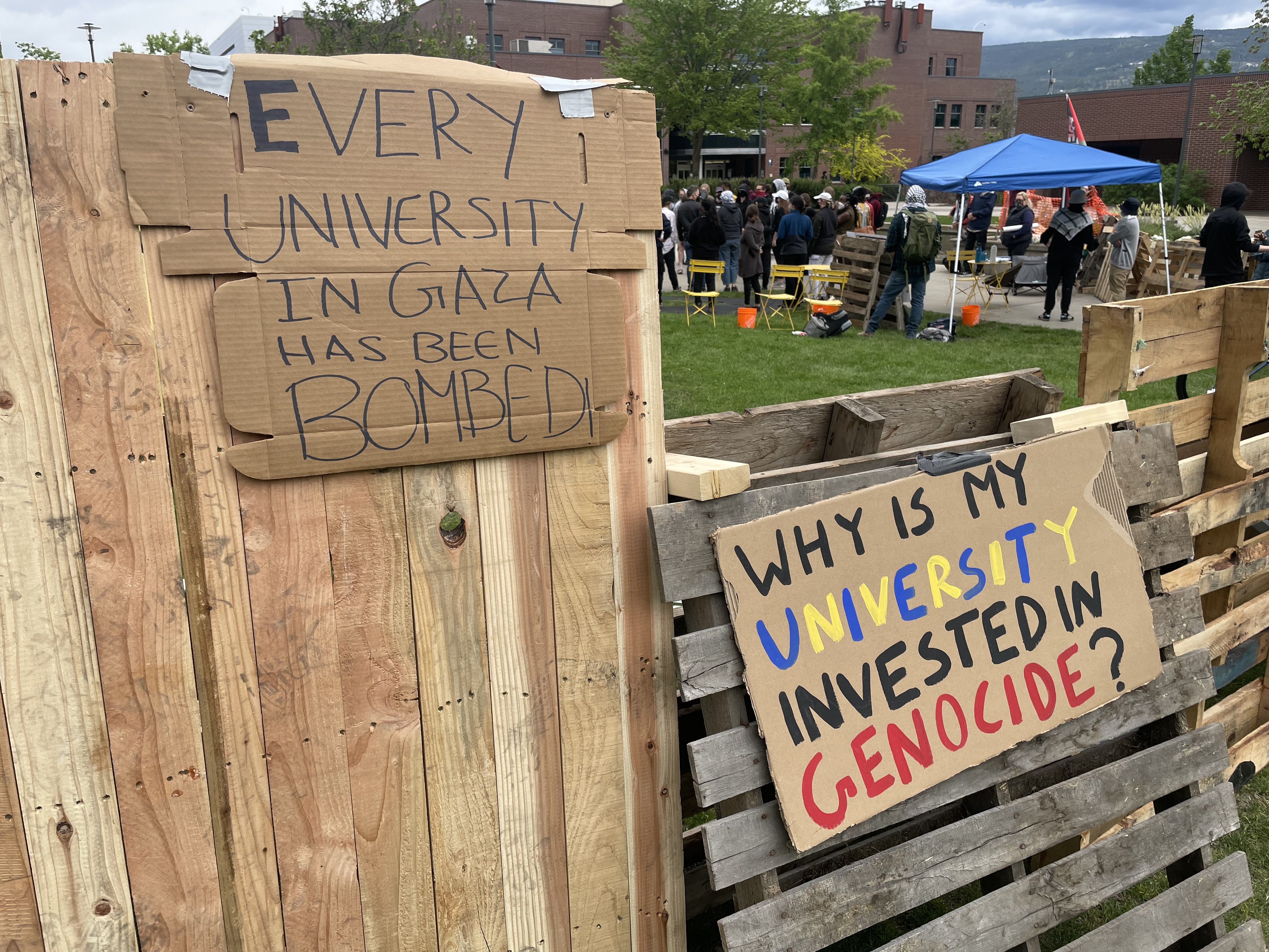 Signs outside of the People's University on the lawn at UBCO campus read "Every University in Gaza has been Bombed" and "Why is my University invested in Genocide?"
