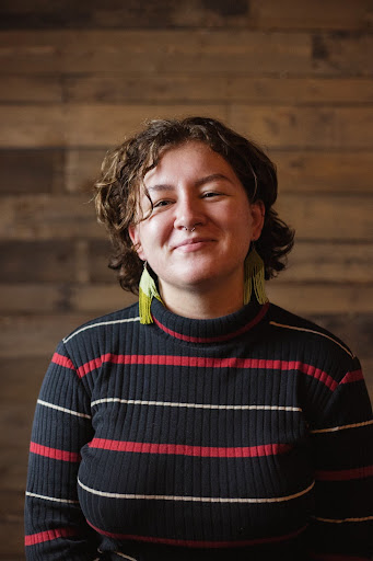Headshot of Dani Pierson wearing a red-black striped shirt and large yellow bead earrings.