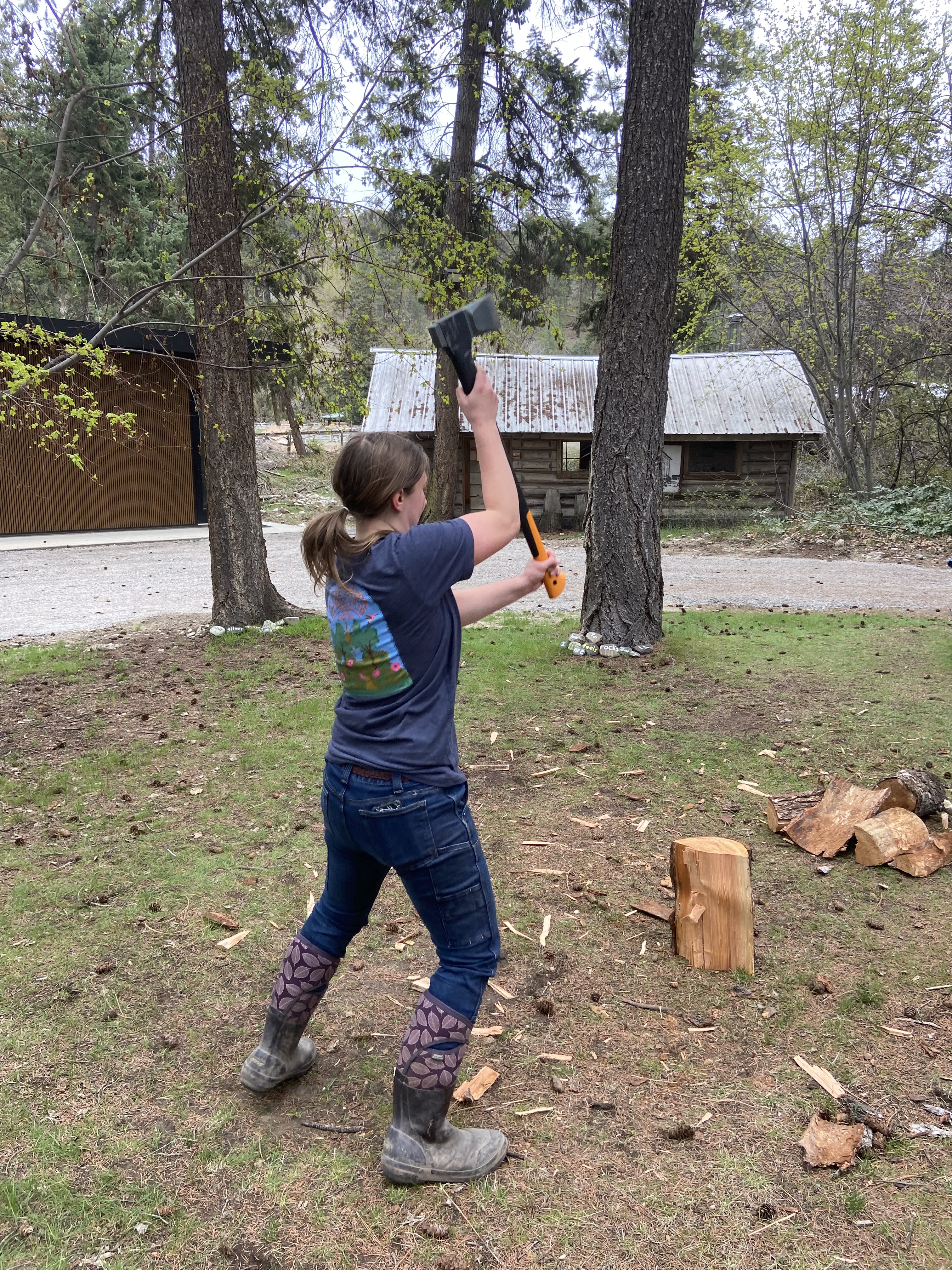 A person in boots, a tshirt and jeans holds aloft an axe, ready to split some wood!