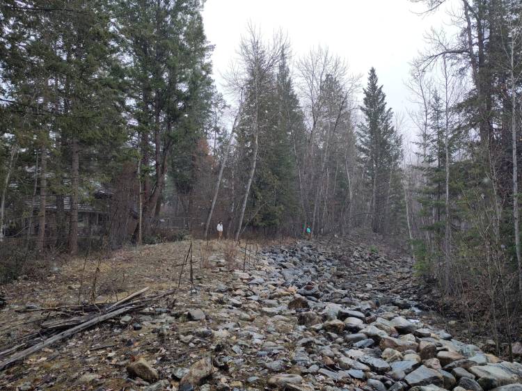 Long shot of Bellevue creek with Tom and Emma looking at the creek, snow is softly falling.