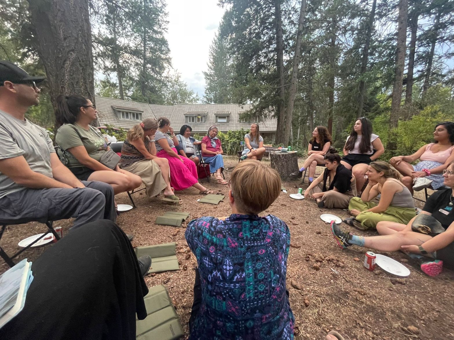 A group of people sitting in a circle outside the FEELed Lab, listening to a story being told