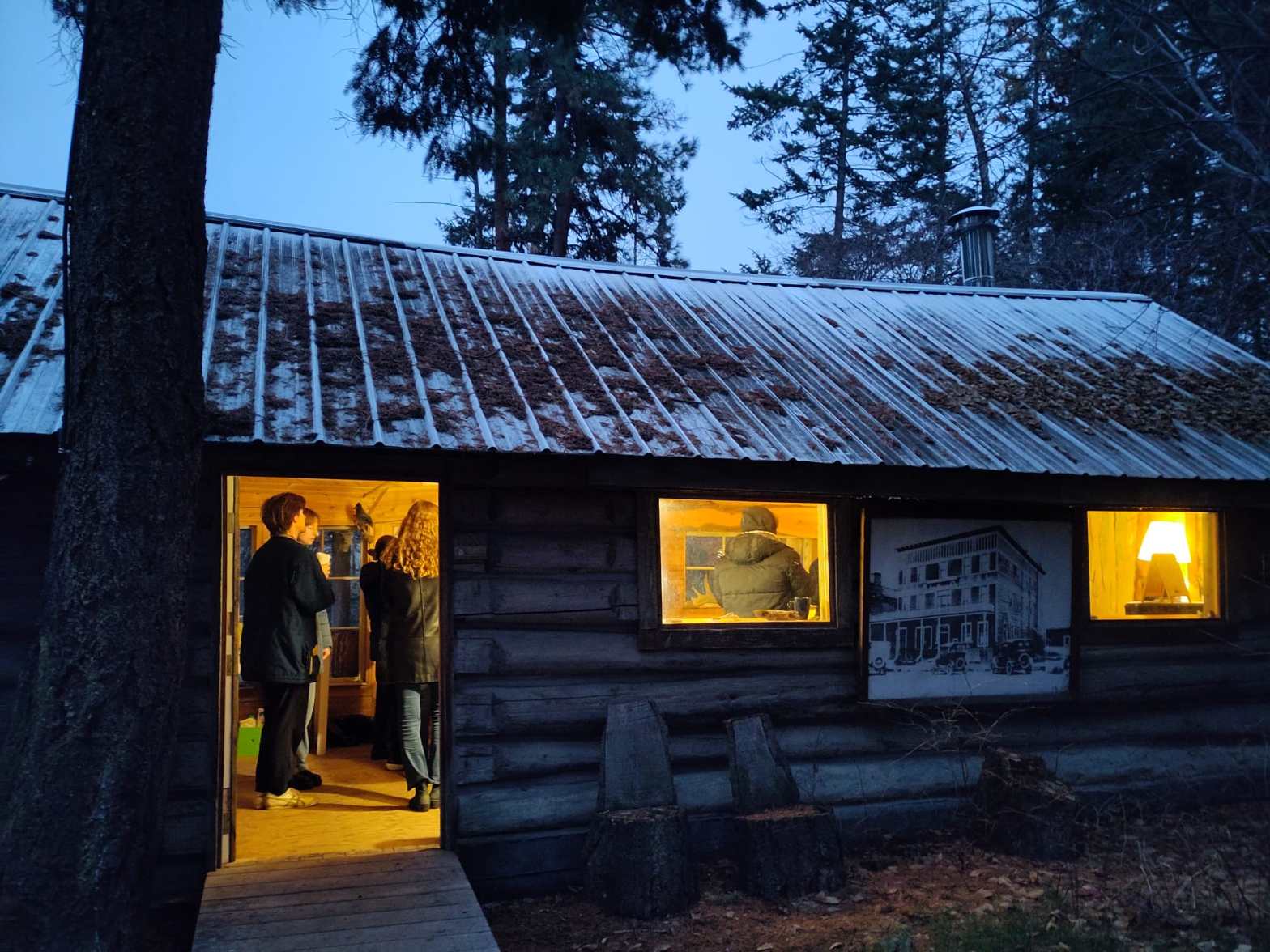 Picture of the warming hut, there is light inside streaming to the outside where it is getting dark