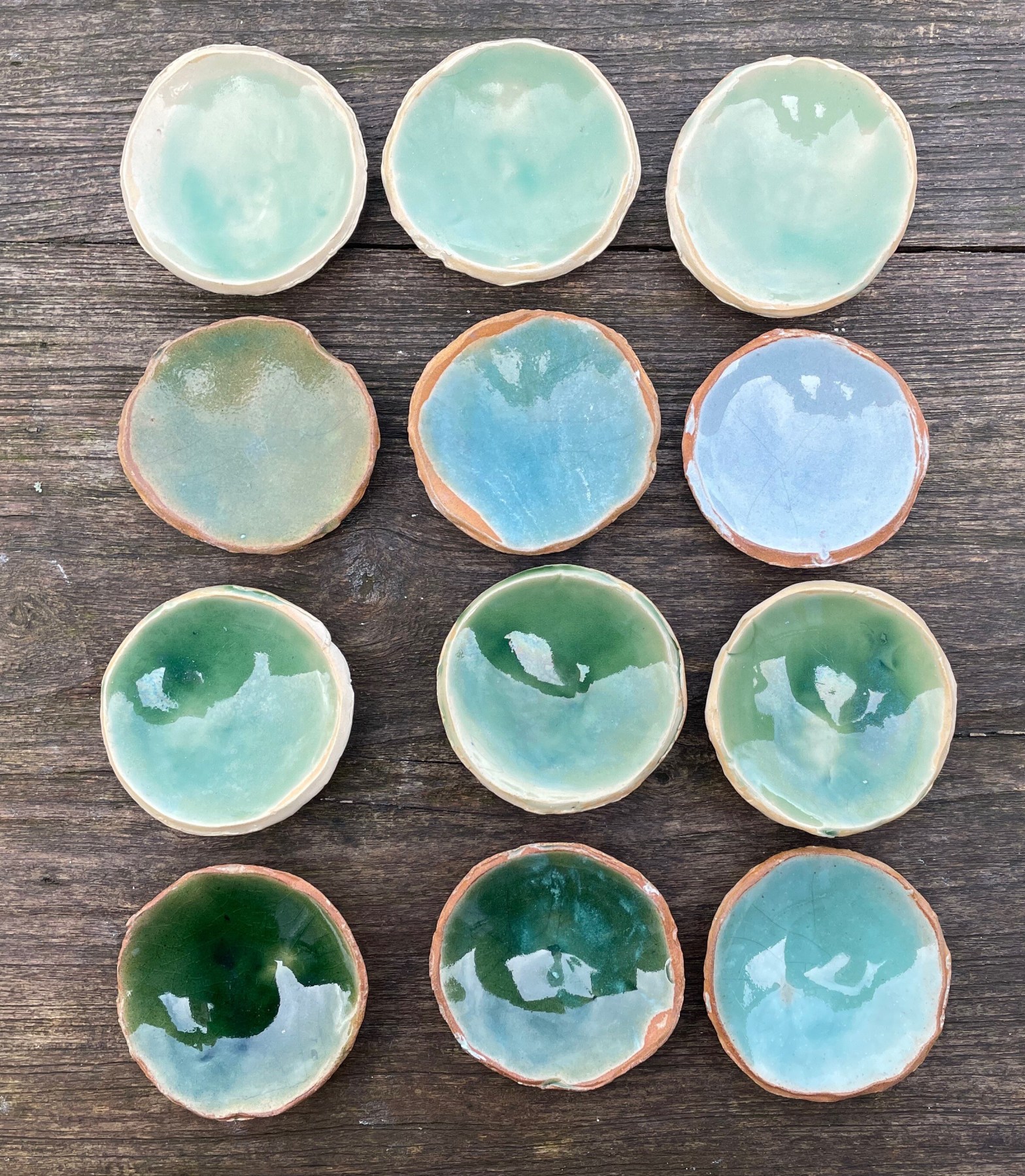 top view of a series of small ceramic vessels with blueish green glazes in different hues