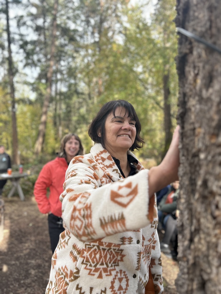 Kelly standing next to a large tree and holding her hand onto it.