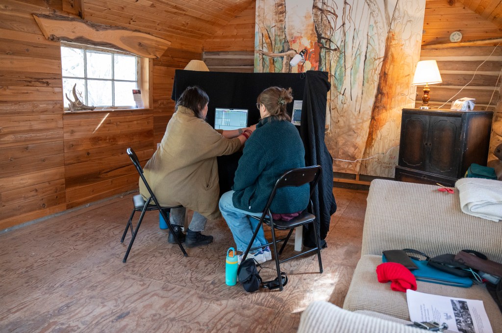 Recording booth set-up in the schoolhouse featuring a table covered in black cloth and two chairs, a recording session is currently in progress