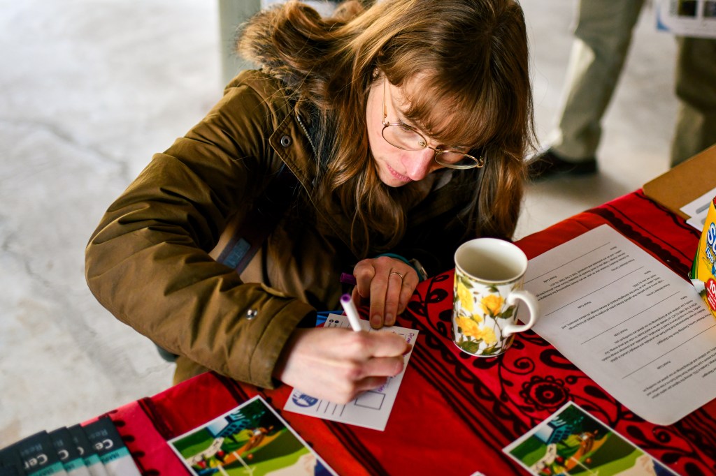 Someone writing a climate justice postcard