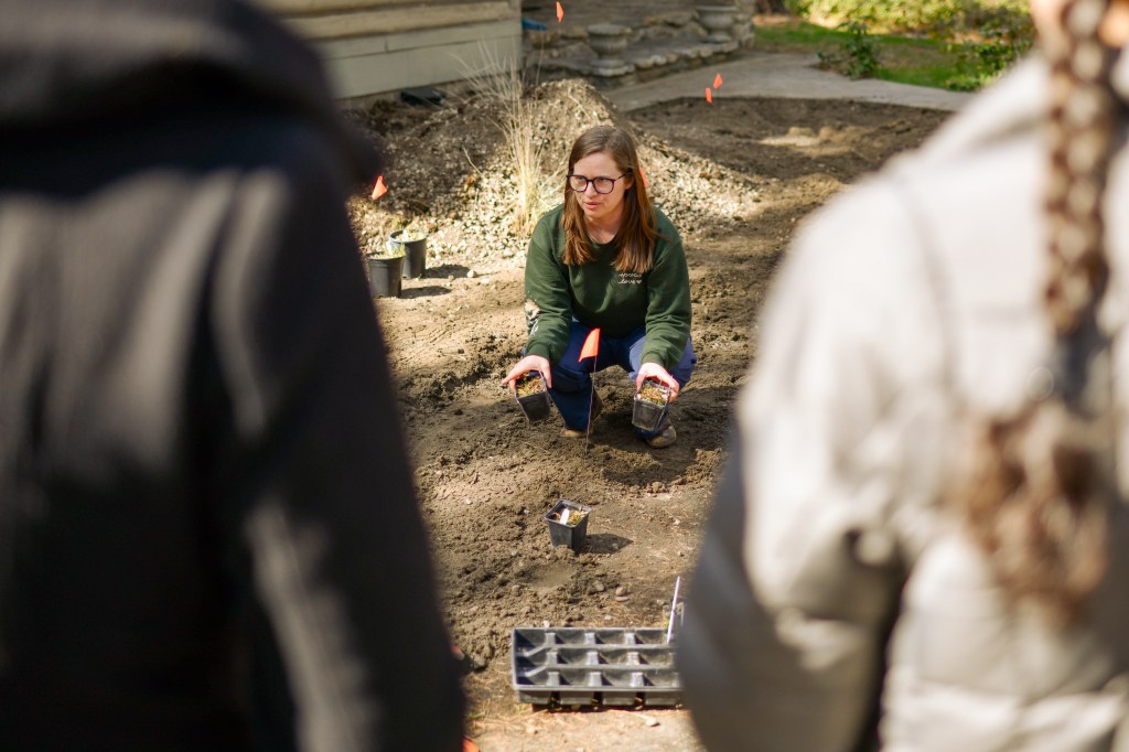Jamie demonstrating the planting with a little seedling kneeling on the ground