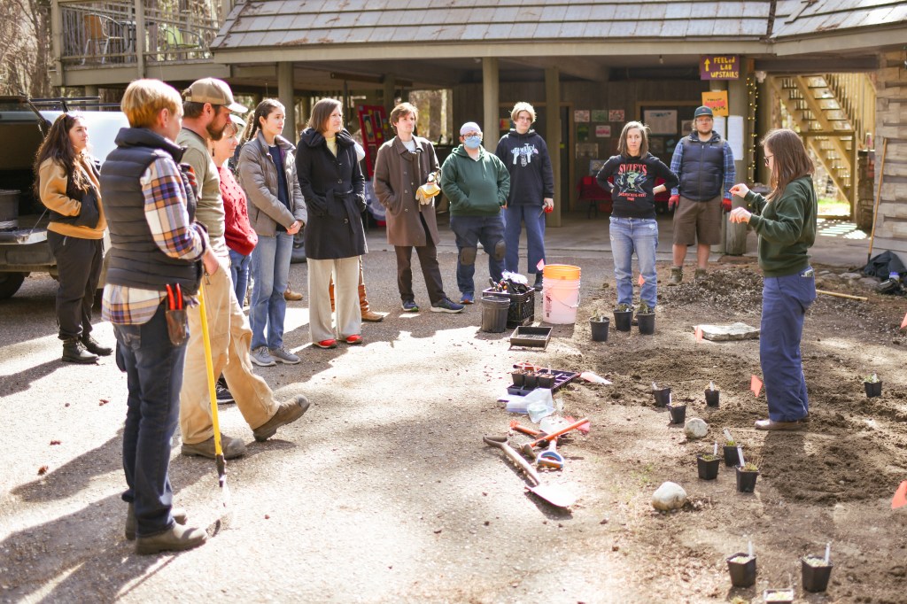 Jamie instructing the planting volunteers who are gathered around her in a halfcircle