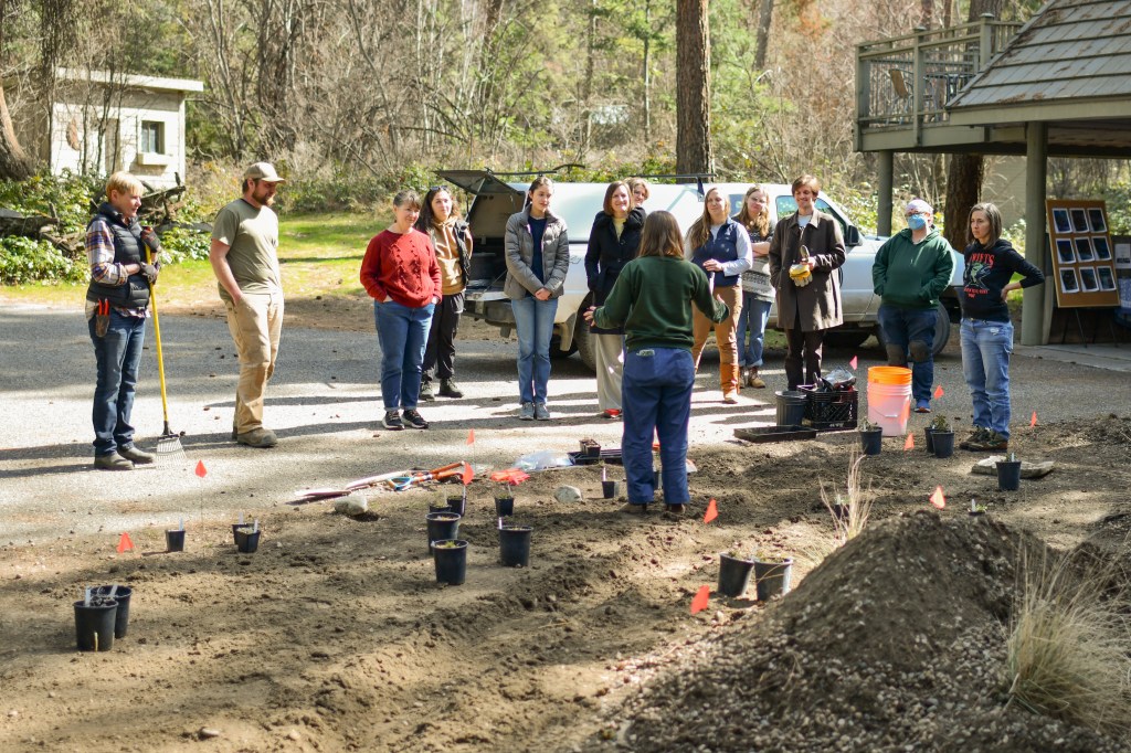 Jamie instructing the planting volunteers who are gathered around her in a halfcircle