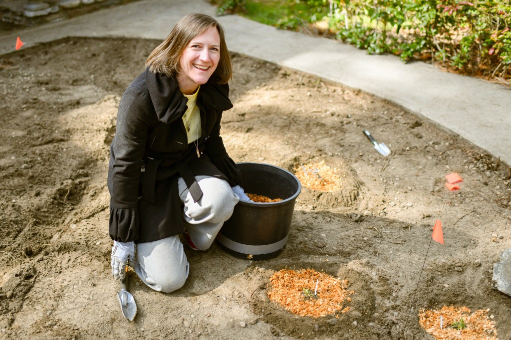 Amy from CCJ smiling up at the camera while planting