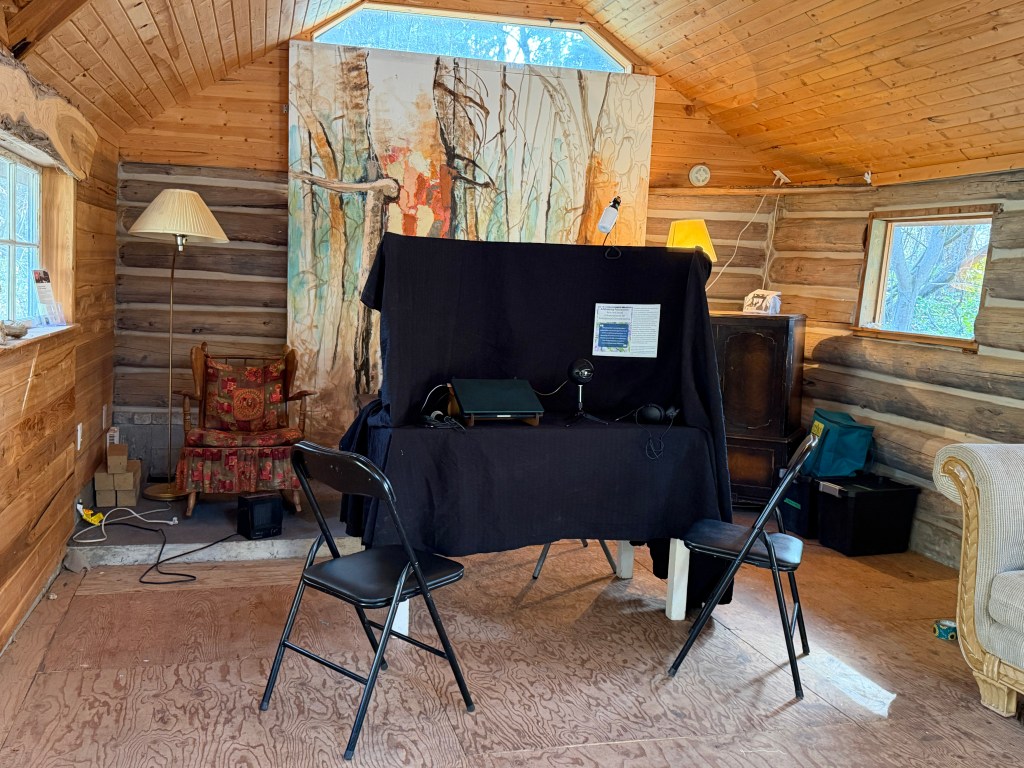 Recording booth set-up in the schoolhouse featuring a table covered in black cloth and two chairs