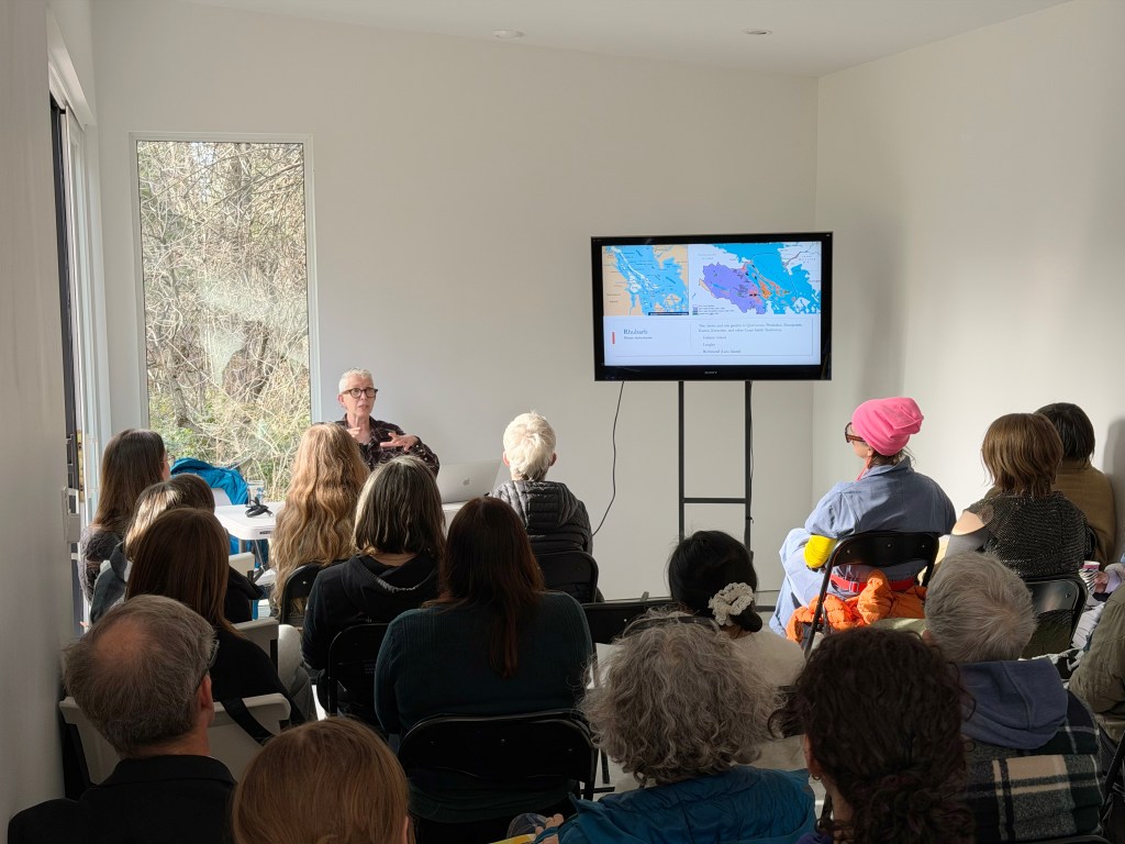 Cate Sandilands giving a talk in Woodhaven studio, the screen behind her shows a map