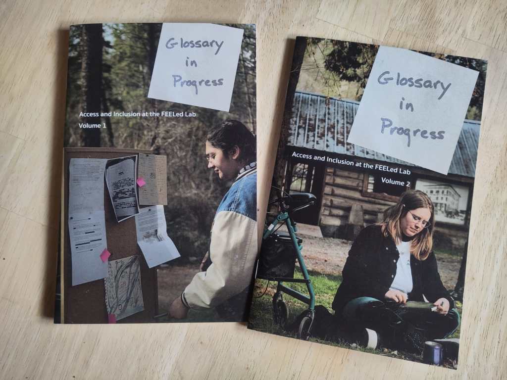 Two chapbooks titled "Glossary in Progress - Access and Inclusion at the FEELed Lab" on a wooden table.