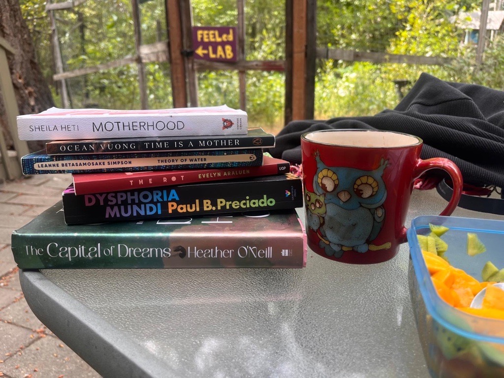 Photo credit: Astrida
A pile of books beside coffee with FEELed Lab sign in the background

