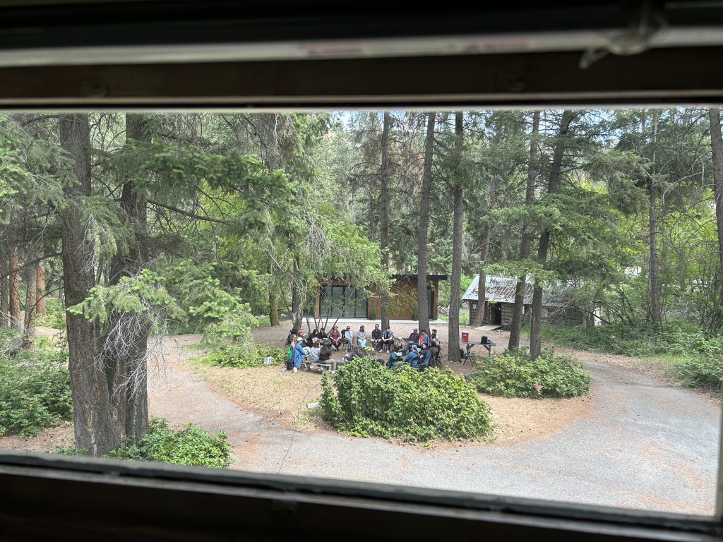 Photo taken through the kitchen window of the FEELed Lab showing a group of people seated around the firepit.