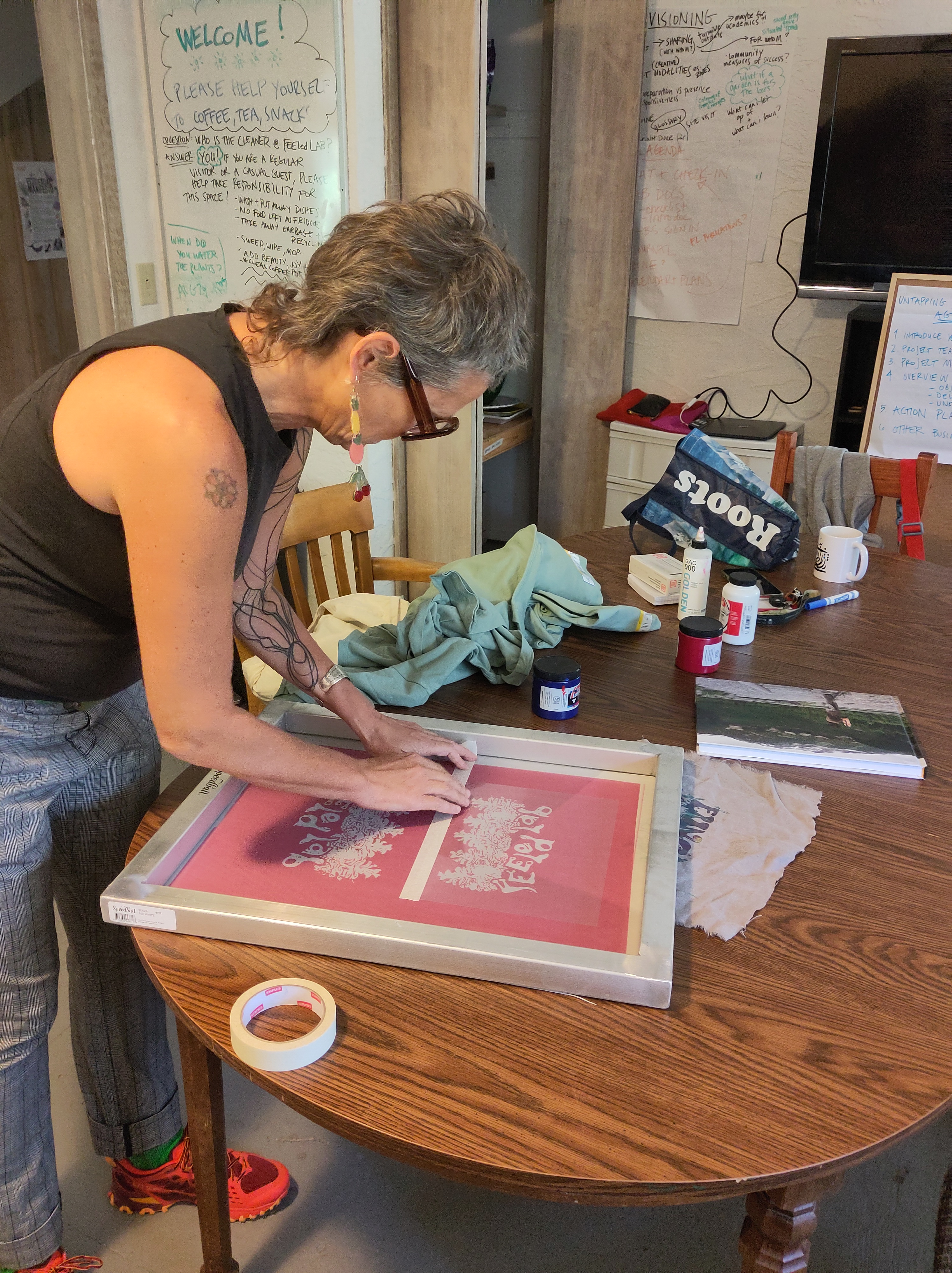 Astrida standing at the FEELed Lab kitchen tabel preparing a silk screen for printing