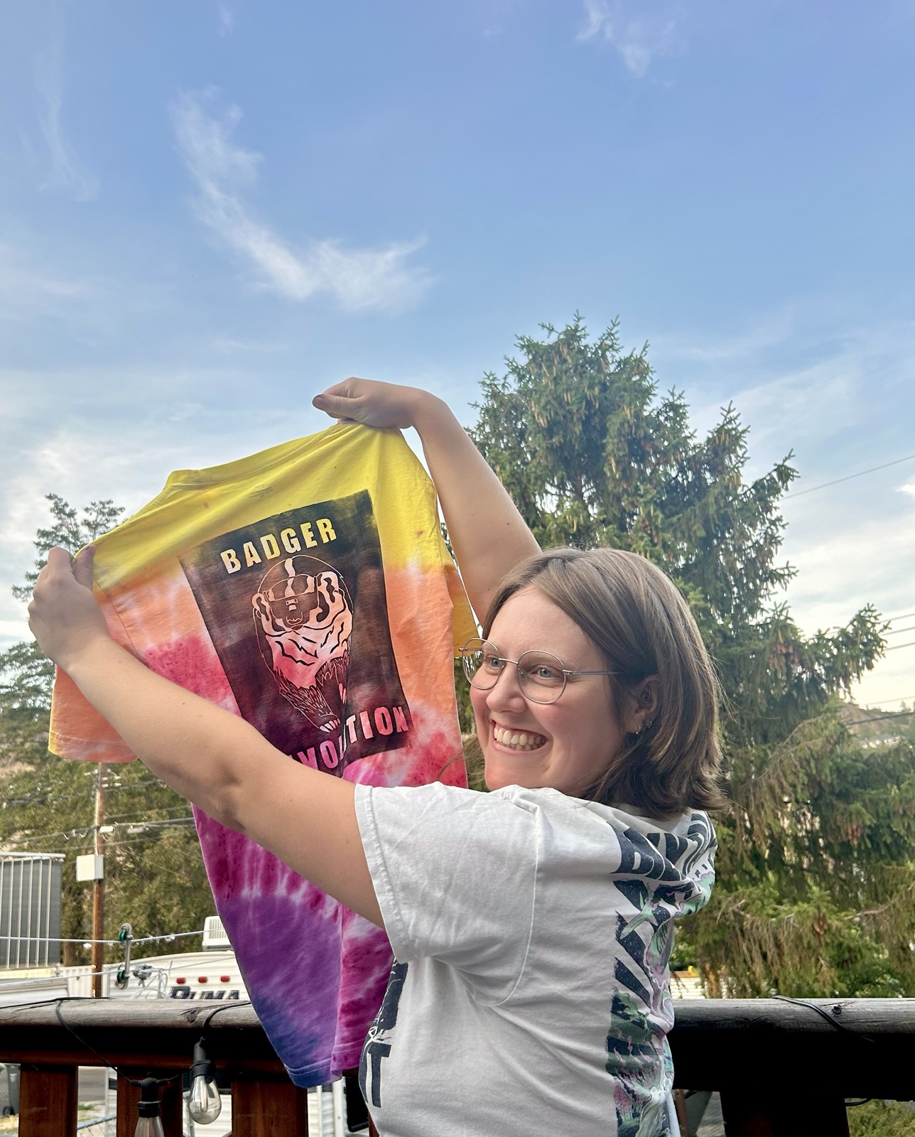 JJ holding up a tie-die shirt with a "Badger Revolution" Screenprint