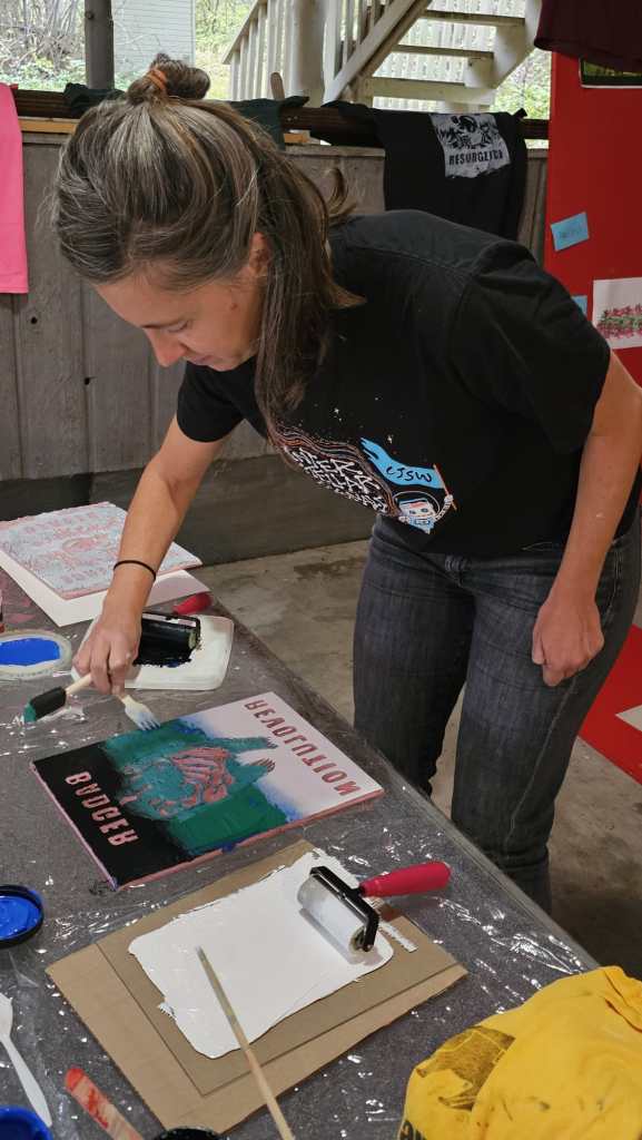 Someone getting ready to print a linocut of the "Badger Revolution" onto a shirt